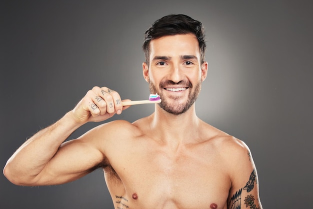 Mondhygiëne man en tandenpoetsen voor gezondheid, wellness en lichaamsverzorging tegen grijze achtergrond Portret mondgezondheid en man met tandenborstel frisse adem en gezond met glimlach en tandpasta