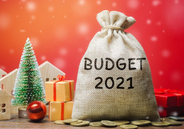 Money bag Budget 2021, Christmas tree, houses and gifts. Accumulating money and planning a budget.