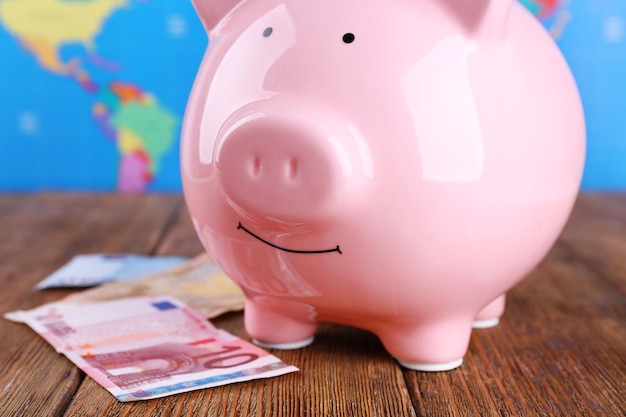 Money box pig on world map background