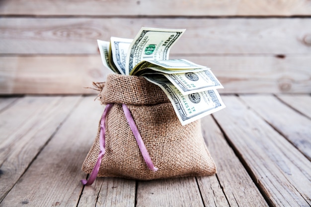 Money in burlap sack on wooden