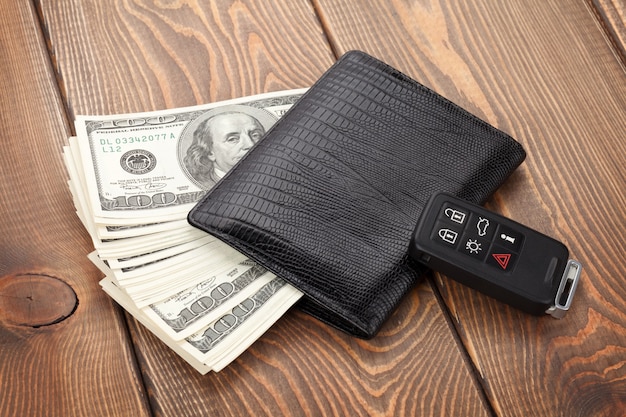 Money cash wallet and car remote key on wooden table