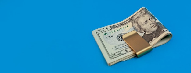 Money clip with dollar bills on blue background