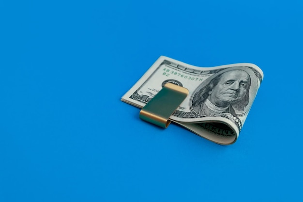 Money clip with dollar bills on blue background