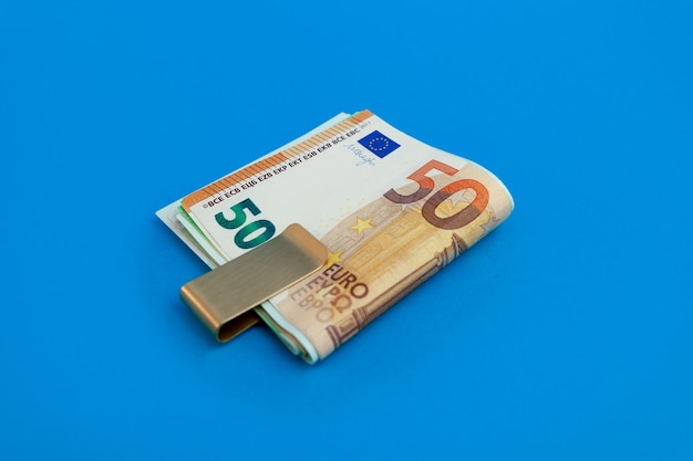 Money clip with euro bills on blue background