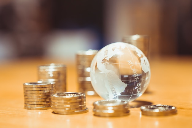 Foto pila di monete di denaro con palla di vetro del mondo