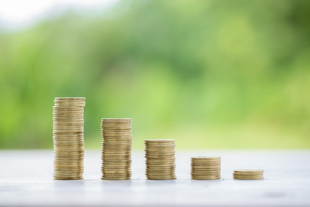 Money coin stacking on wood desk in green background management cash insurance asset and wealth tax accounting budget growth loan financial economic savings for business investments concept