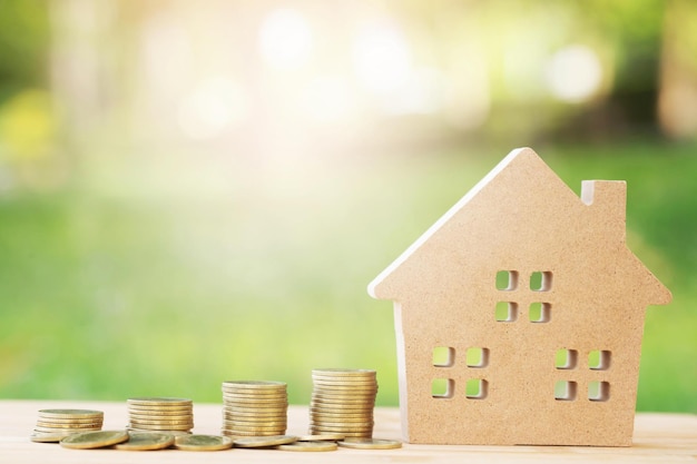 money coins stacked on each other in different positions and home in brown recycled paper model on the wooden table credit financial growing loan to buy a house concept saving money