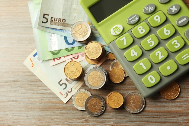 Money concept Green calculator with banknotes and coins on wooden table