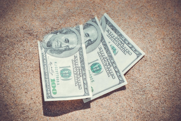 Money dolars half covered with sand lie on beach closeup