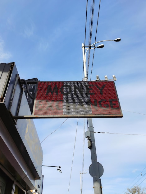 MONEY EXCHANGE electronic sign with illuminated letters on the shop against the sky background