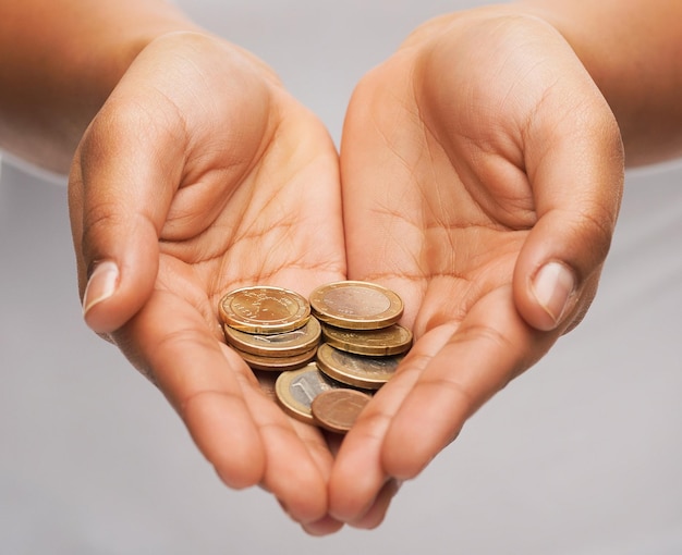 お金と財政の概念-ユーロ硬貨を示す女性のカップ状の手のクローズアップ