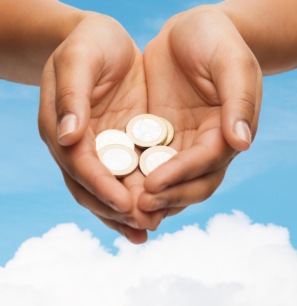 Photo money and finances concept - close up of womans cupped hands showing euro coins
