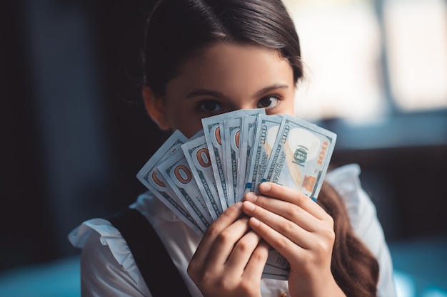 Money. Girl holding dollars and closing her face