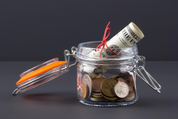 Money in a glass jar with a lid on a dark background Savings concept