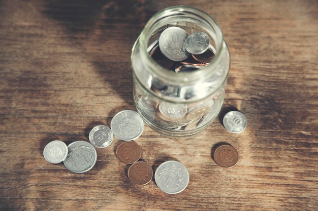 Money on glass jar on wooden table