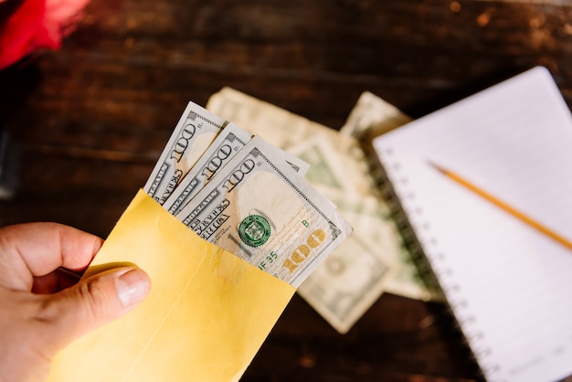 Photo money - a hand holding an envelope with $100 dollar bills