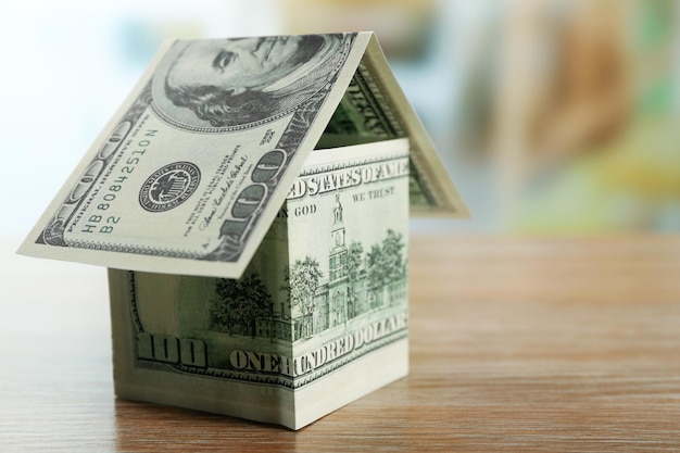 Money house on wooden table close up