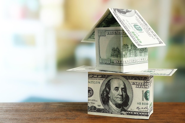 Money house on wooden table close up