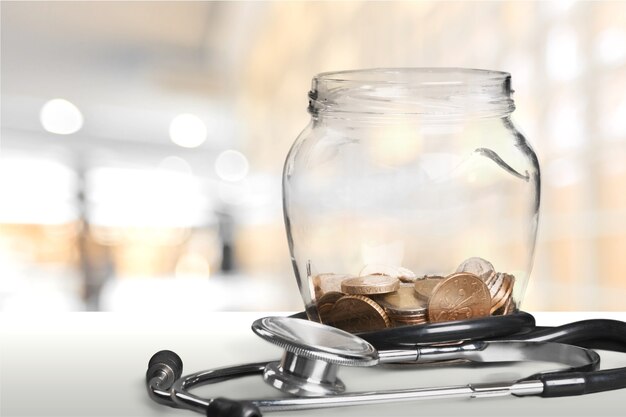 Money jar with coins and stethoscope