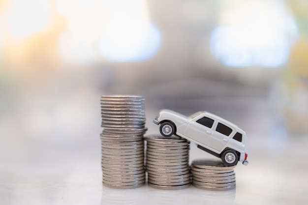 Money, Loan and Saving. CLose up of white miniature mini car toy on top of row of stack of silver coins.