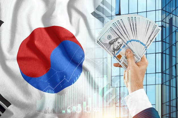 Money in a man's hand against the background of the flag of South Korea