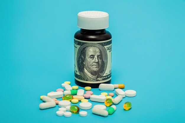 Money and pills of different colors on a blue background the rise in the cost of medical care the