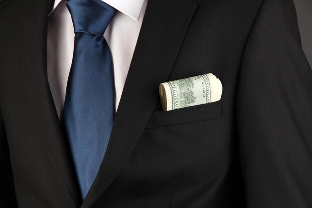 Money in pocket of businessman on black background