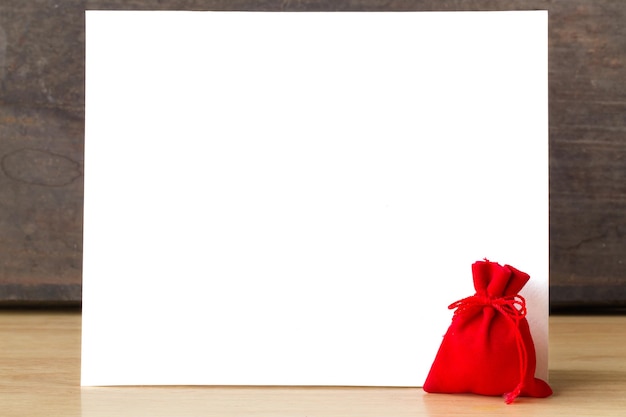Soldi in borsa rossa con sfondo di carta bianca per aggiungere un messaggio di testo biglietto di auguri per il capodanno cinese su un tavolo di legno