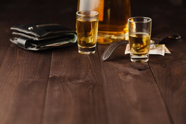 Money and whiskey on wooden table. Close-up view