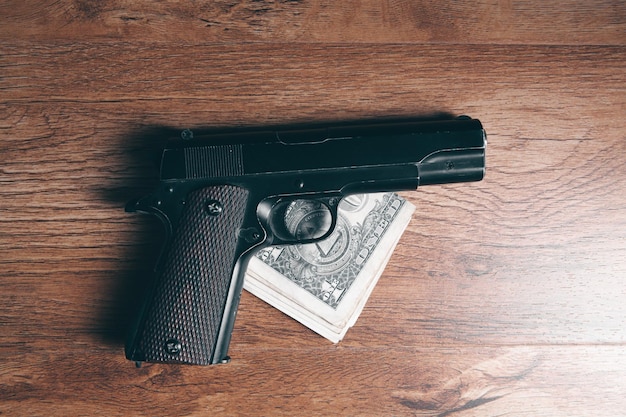 Photo money with gun on the wooden table