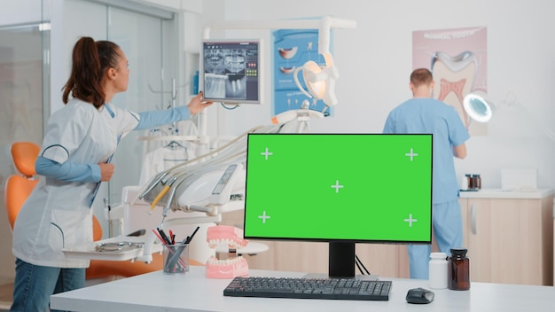 Monitor met groen scherm op bureau in tandartspraktijk voor tandheelkundige controle en mondverzorging. Computer met horizontale chromasleutel en modelsjabloon voor gebitsbehandeling en gebitsverzorging