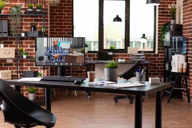 Monitor showing video call with man on desk in space. Online video teleconference to have remote conversation with colleague on computer in business office. Videoconference meeting