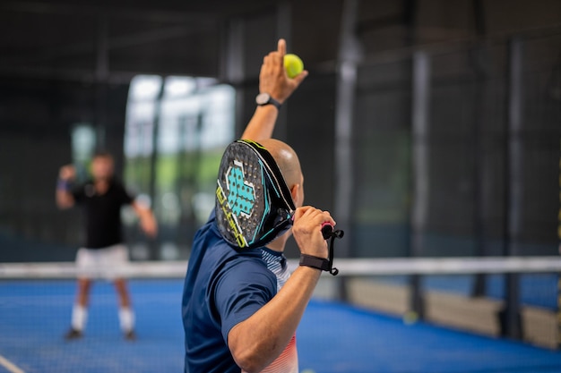 Photo monitor teaching padel class to man his student - trainer teaches boy how to play padel