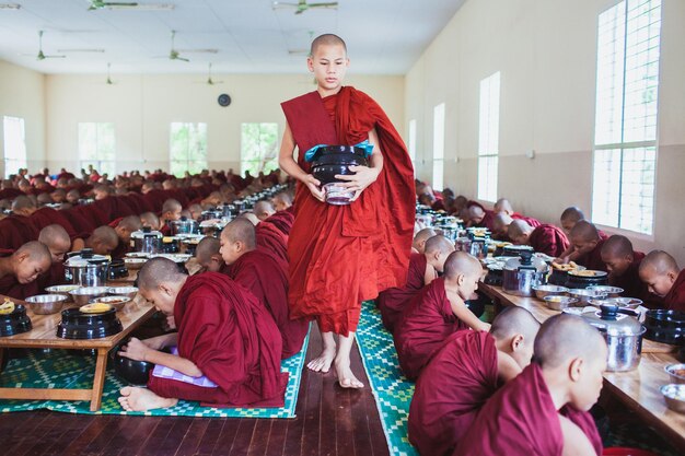 A monk in a classroom with a bowl of water in his hands.