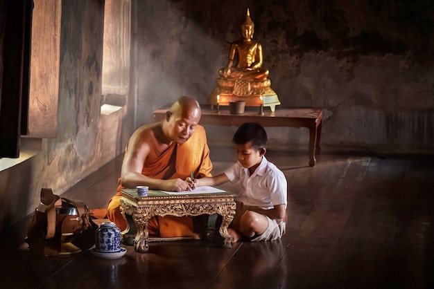 僧侶がアユタヤの寺院で水曜日に興味のある子供たちに宗教を教えています。