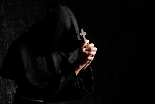 A monk praying with a rosary and crucifix in his hand