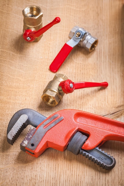 Monkey wrench and plumbing fixtures on wooden board