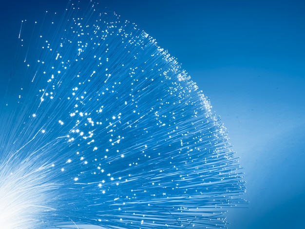 Monochrome blue color toned image with copy-space. futuristic technological , closeup on the end of optical fiber network cable on dark blue to white gradient, space for your text