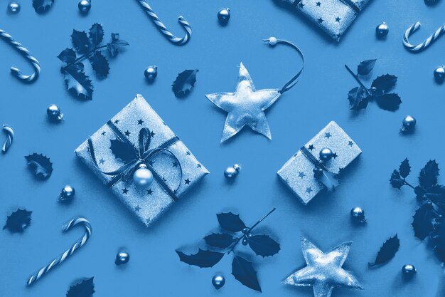 Muro di natale di colore blu monocromatico. piatto di natale geometrico alla moda disteso su una parete di carta con bastoncini di zucchero, ramoscelli di agrifoglio e abete, stelle di legno e bigiotteria di vetro. buone vacanze invernali!
