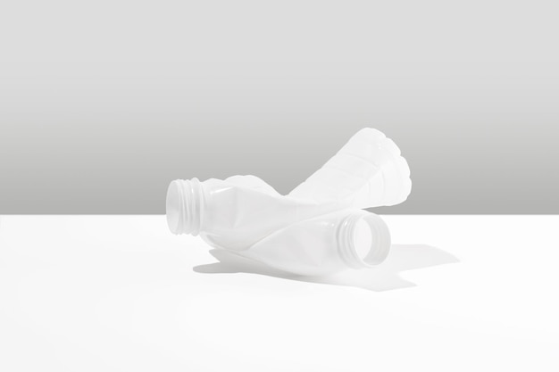 Монохромная композиция из пластиковых бутылок, лежащих на белой поверхности негативное воздействие на природу концепция экологического ущерба идея загрязнения земли пластиком копирование пространства