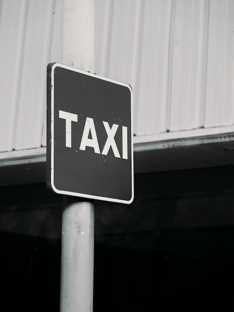 Monochrome image of a taxi sign against industrial background