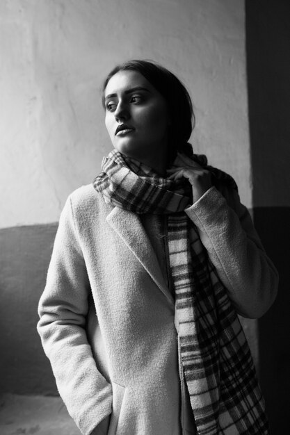 Monochrome interior portrait of a stylish brunette woman wears stylish outfit