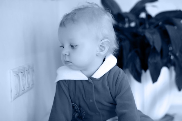 Photo monochrome photo of little blond child in the kitchen sits on a table