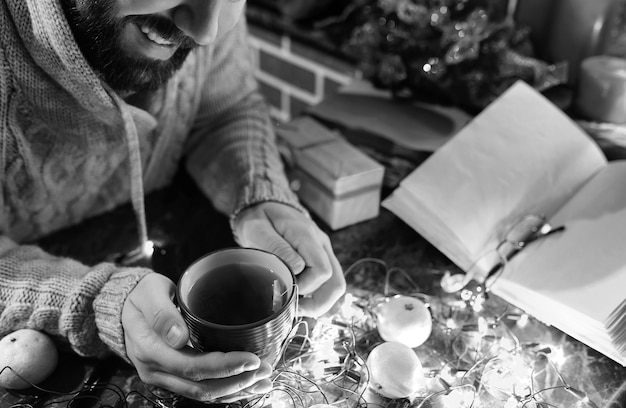 Photo monochrome photo of man with a blank book in his hands for the new year's table with decorations