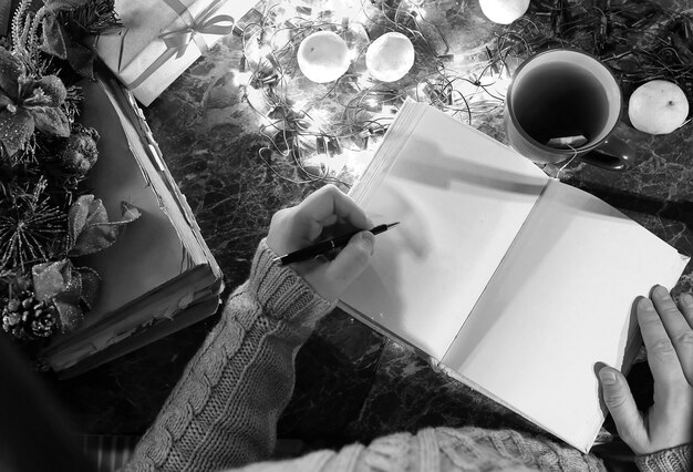 Photo monochrome photo of man with a blank book in his hands for the new year's table with decorations