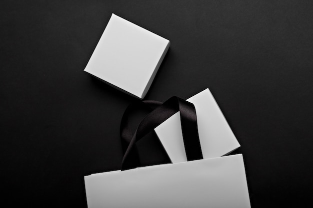 Фото monochrome фото белой бумажной сумки и коробок на черной предпосылке. место для вашего логотипа