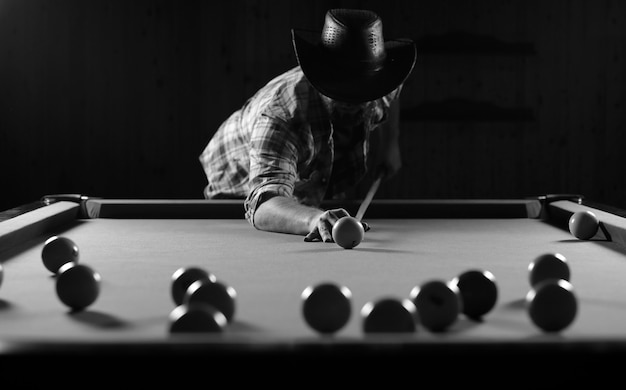 Monochrome photo of young man playing billiards