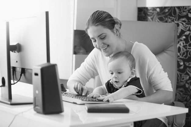 Photo monochrome portrait of young mother taking care of baby and working