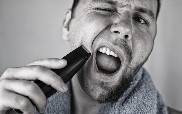 Monochrome textured portrait bearded man shaving electric