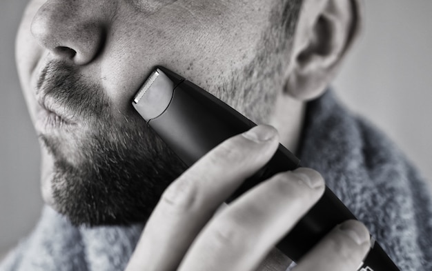 Monochrome textured portrait bearded man shaving electric